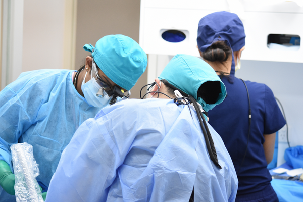 dentist students in scrubs working on patient