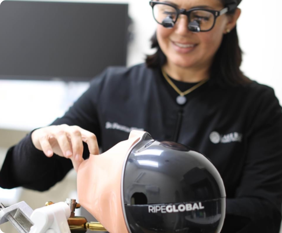 head shot of woman dentist smiling in glasses looking at plastic dentist model
